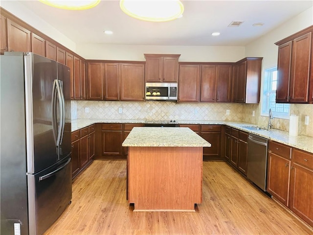 kitchen featuring stainless steel appliances, a center island, sink, and light wood-type flooring