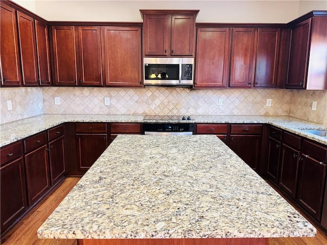 kitchen featuring light stone countertops, a center island, and oven