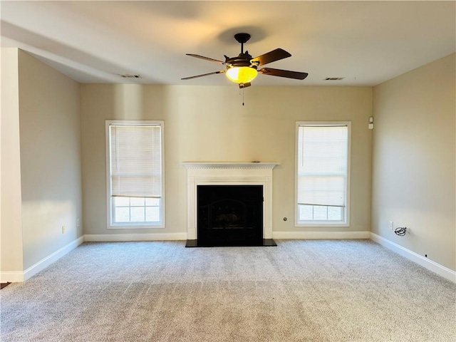 unfurnished living room featuring ceiling fan, a healthy amount of sunlight, and light carpet