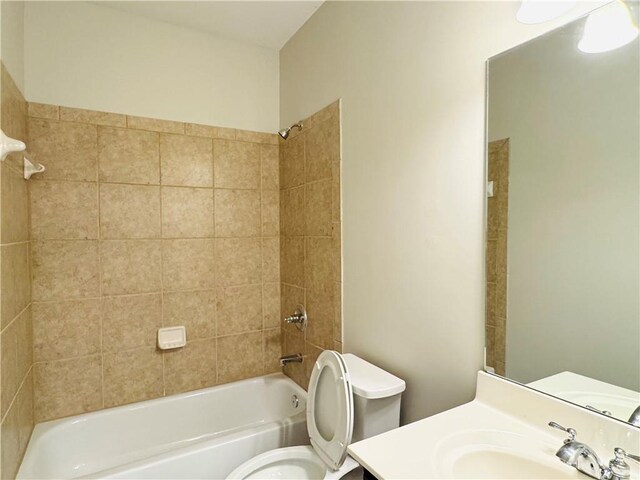 full bathroom with tiled shower / bath, vanity, and toilet