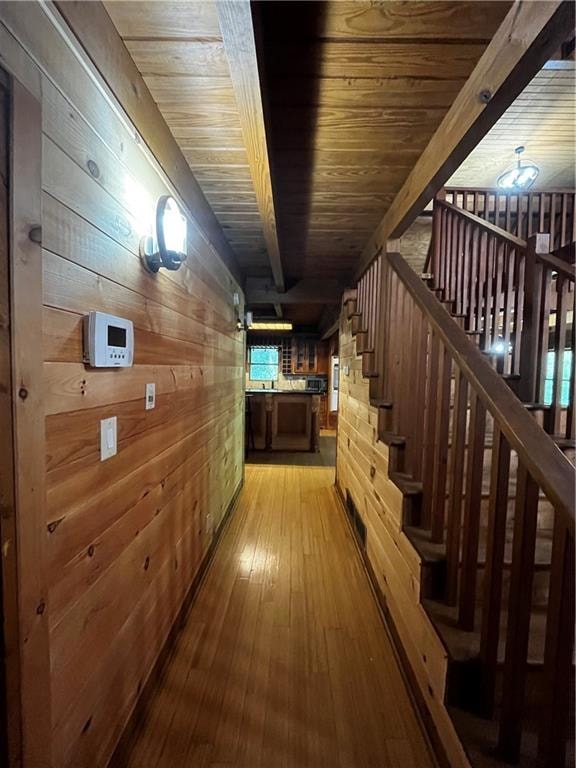 hall featuring wood-type flooring, beam ceiling, wooden walls, and wood ceiling