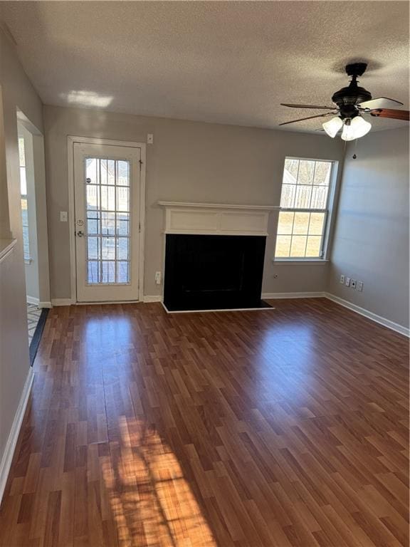 unfurnished living room featuring ceiling fan, dark wood-type flooring, and a textured ceiling