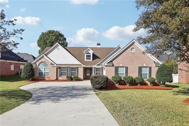 view of front of house featuring driveway, brick siding, and a front yard