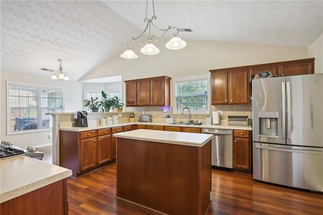 kitchen with dark wood finished floors, a peninsula, stainless steel appliances, and a sink