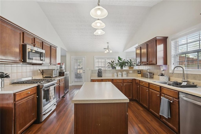 kitchen with lofted ceiling, a sink, stainless steel appliances, light countertops, and dark wood-type flooring