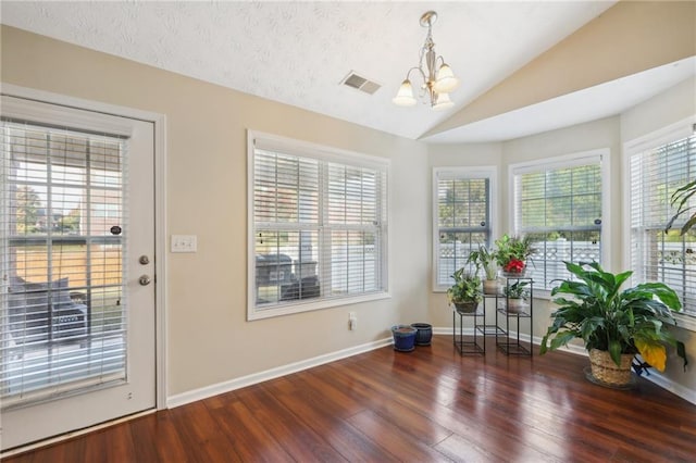 foyer with visible vents, plenty of natural light, lofted ceiling, and wood finished floors