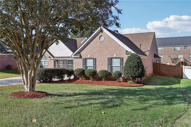 view of front of property featuring brick siding, a front lawn, and fence