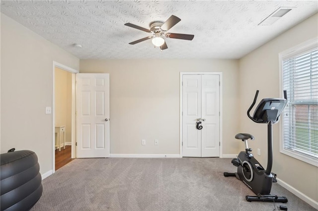 workout room with carpet, baseboards, visible vents, ceiling fan, and a textured ceiling