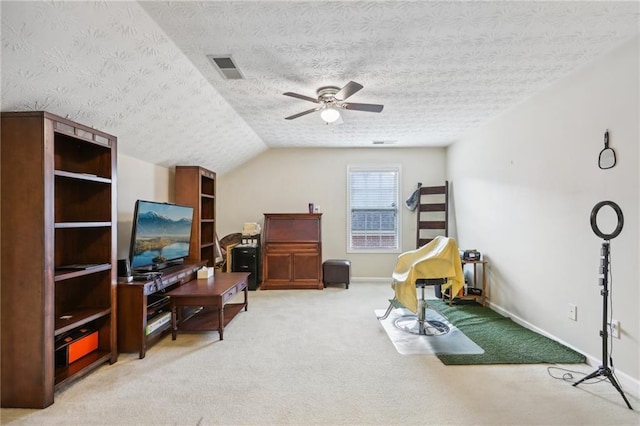 interior space with a ceiling fan, visible vents, baseboards, lofted ceiling, and light colored carpet