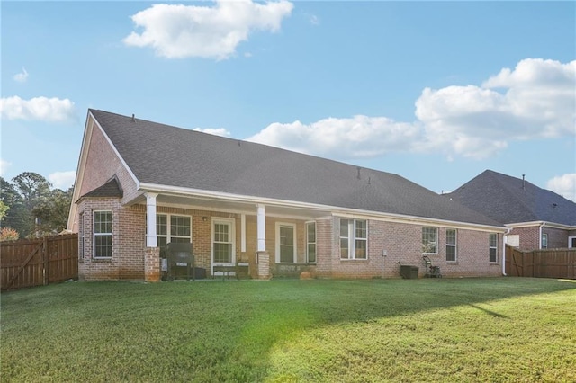 back of house with a lawn, a fenced backyard, brick siding, and a shingled roof