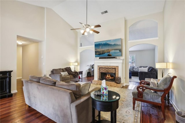 living room with visible vents, high vaulted ceiling, dark wood-style floors, a fireplace, and baseboards