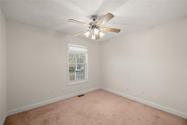 spare room featuring a textured ceiling, baseboards, light colored carpet, and visible vents