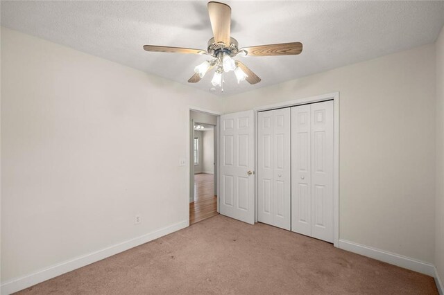 unfurnished bedroom featuring a closet, baseboards, ceiling fan, a textured ceiling, and carpet