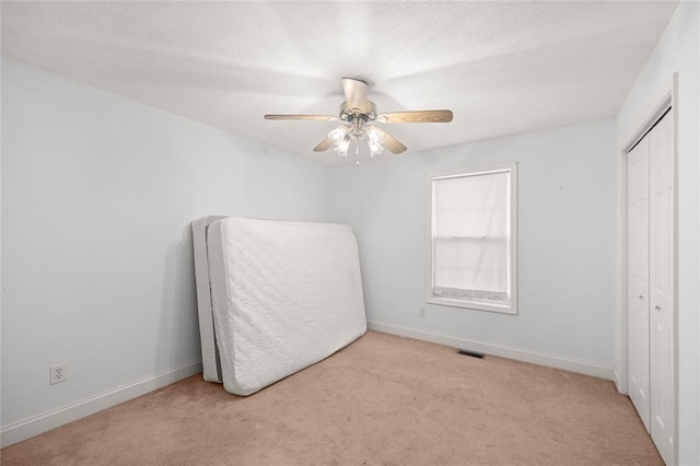 unfurnished bedroom featuring carpet flooring, ceiling fan, baseboards, visible vents, and a closet