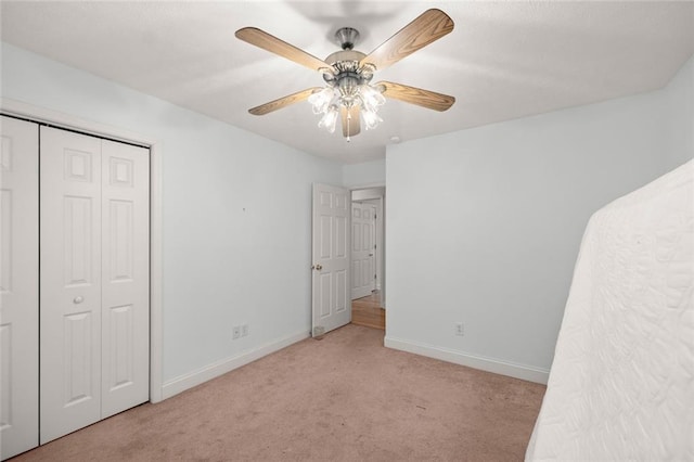 unfurnished bedroom with carpet flooring, baseboards, ceiling fan, and a closet