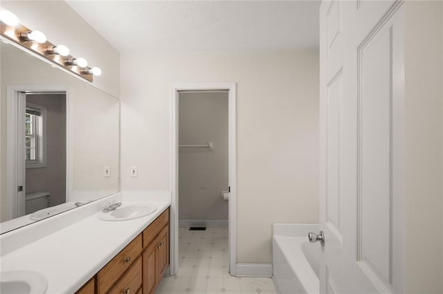 full bath featuring double vanity, baseboards, a bathing tub, tile patterned floors, and a sink