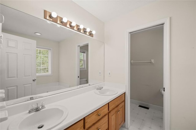 bathroom with double vanity, visible vents, a sink, and a bath