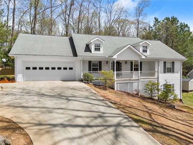 cape cod-style house with a porch, a garage, roof with shingles, and driveway