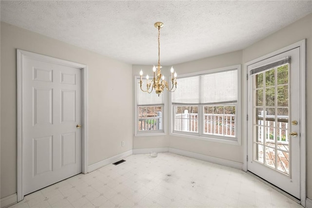 unfurnished dining area featuring a notable chandelier, tile patterned floors, a textured ceiling, baseboards, and visible vents