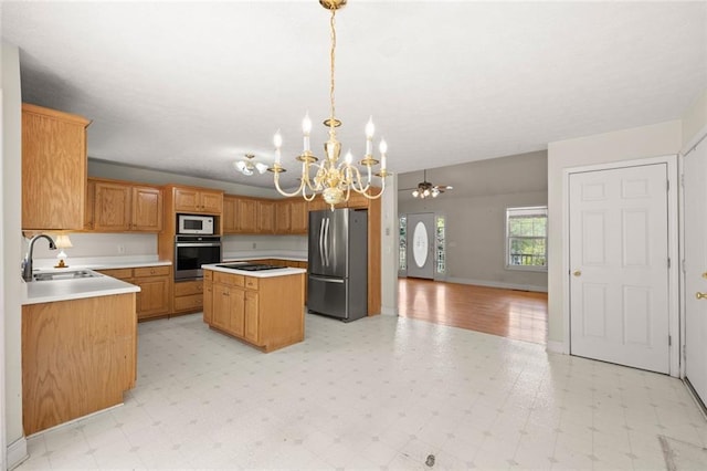 kitchen featuring a notable chandelier, a sink, a center island, stainless steel appliances, and light floors