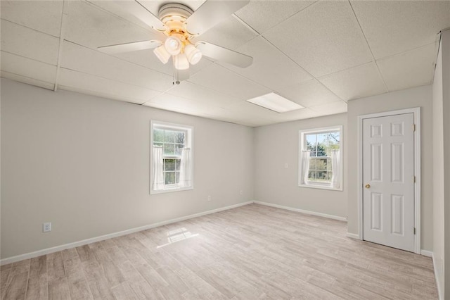 spare room featuring plenty of natural light, a ceiling fan, light wood finished floors, and a paneled ceiling