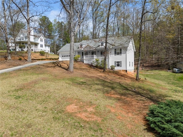 view of front of home featuring a garage, covered porch, driveway, and a front yard