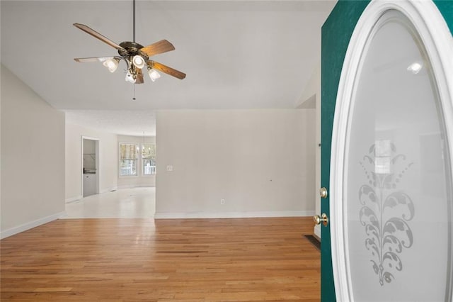 empty room featuring light wood-type flooring, baseboards, ceiling fan with notable chandelier, and lofted ceiling
