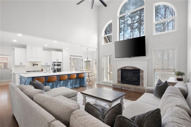 living room featuring a chandelier, recessed lighting, a fireplace, baseboards, and light wood-type flooring