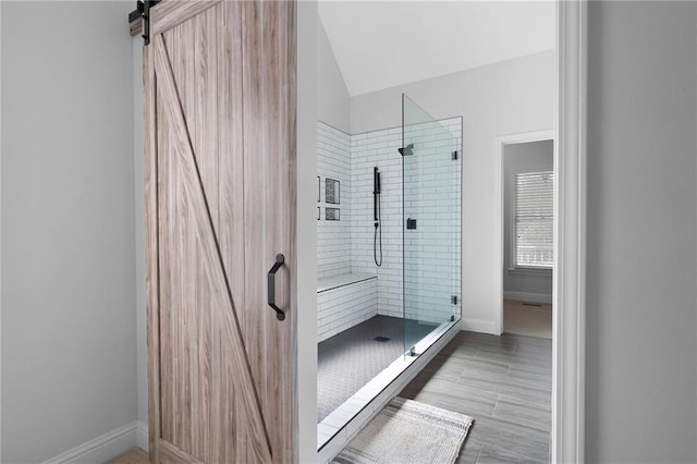 bathroom with lofted ceiling, a stall shower, and baseboards