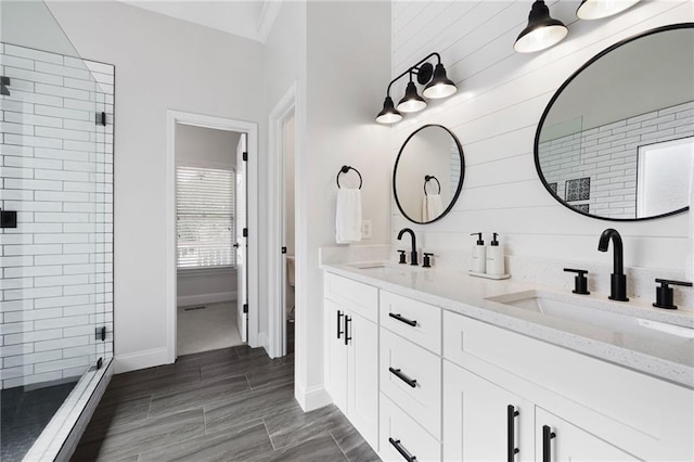 bathroom with double vanity, a stall shower, baseboards, and a sink