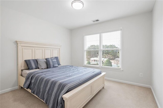 bedroom with baseboards, visible vents, and light colored carpet