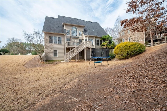 back of property featuring a balcony, a trampoline, stairway, and a deck