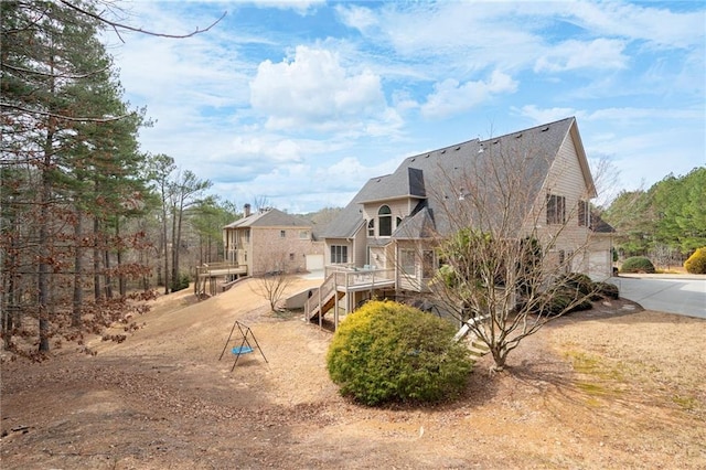 back of house with a garage, driveway, stairway, and a deck