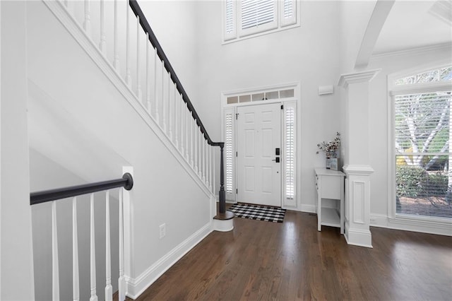 foyer entrance with a high ceiling, wood finished floors, baseboards, stairs, and decorative columns