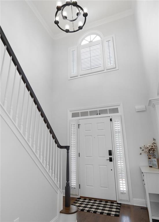 entryway with ornamental molding, stairway, plenty of natural light, and dark wood finished floors