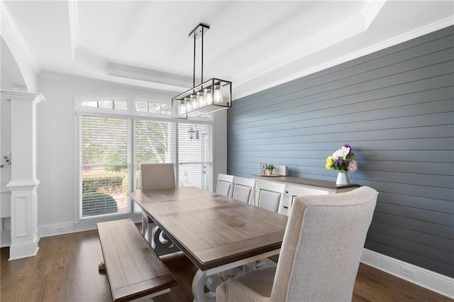 dining space featuring decorative columns, crown molding, a raised ceiling, and dark wood finished floors