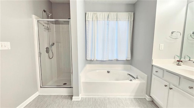 full bath with a shower stall, a bath, vanity, and baseboards