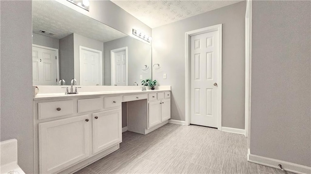 bathroom featuring double vanity, baseboards, and a textured ceiling
