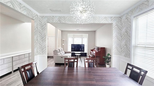 dining space featuring wallpapered walls, ornamental molding, wood finished floors, and a chandelier