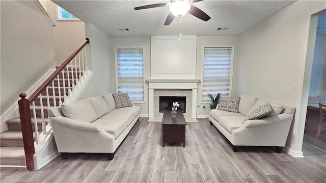 living area featuring stairs, a ceiling fan, wood finished floors, a textured ceiling, and baseboards