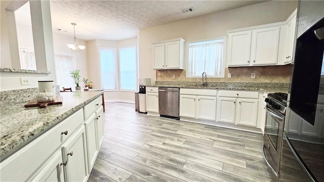 kitchen with stainless steel appliances, a sink, white cabinetry, plenty of natural light, and a textured ceiling