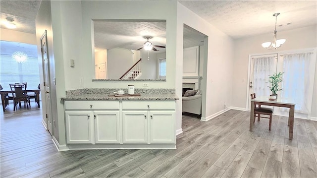 bathroom with wood finished floors, a textured ceiling, ceiling fan, a fireplace, and baseboards