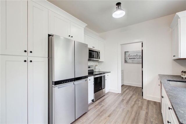 271 Moorings Run, Jasper, GA 30143 - kitchen with stainless steel appliances, light wood-style floors, white cabinets, backsplash, and dark countertops