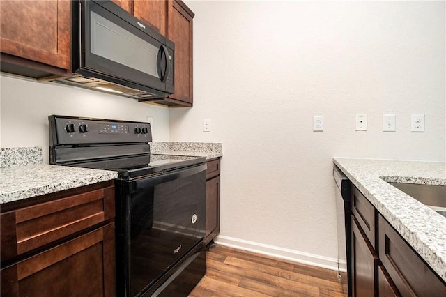 kitchen with black appliances, light stone countertops, dark wood-type flooring, and dark brown cabinetry