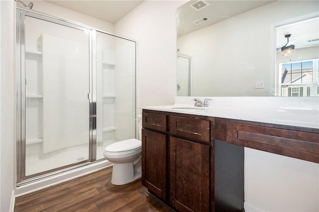 bathroom with hardwood / wood-style floors, toilet, vanity, and an enclosed shower