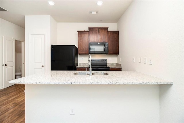 kitchen featuring light stone countertops, sink, black appliances, and kitchen peninsula