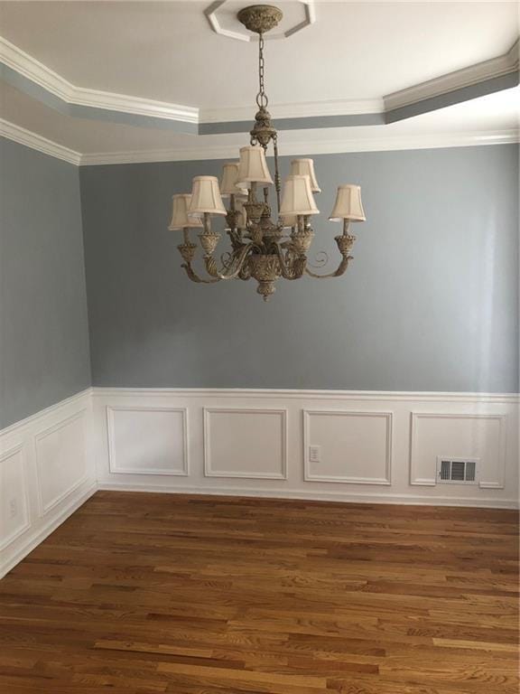 spare room with a chandelier, ornamental molding, and dark hardwood / wood-style floors