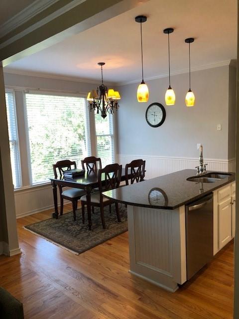 kitchen featuring sink, dishwasher, crown molding, and pendant lighting