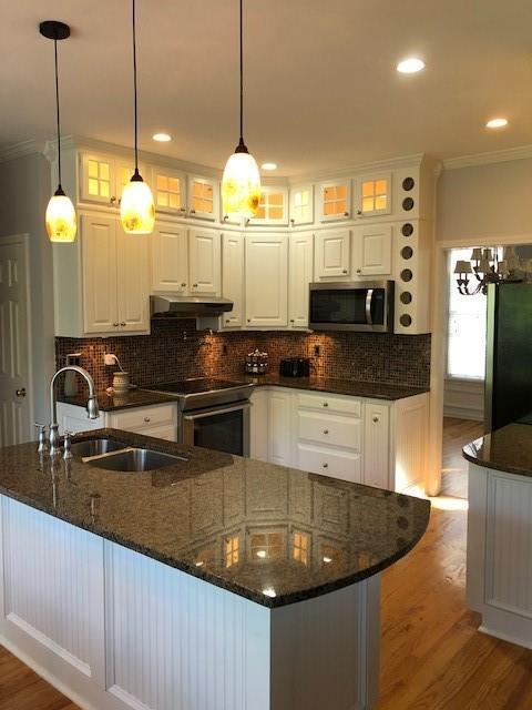 kitchen with decorative light fixtures, white cabinets, stainless steel appliances, and dark stone countertops