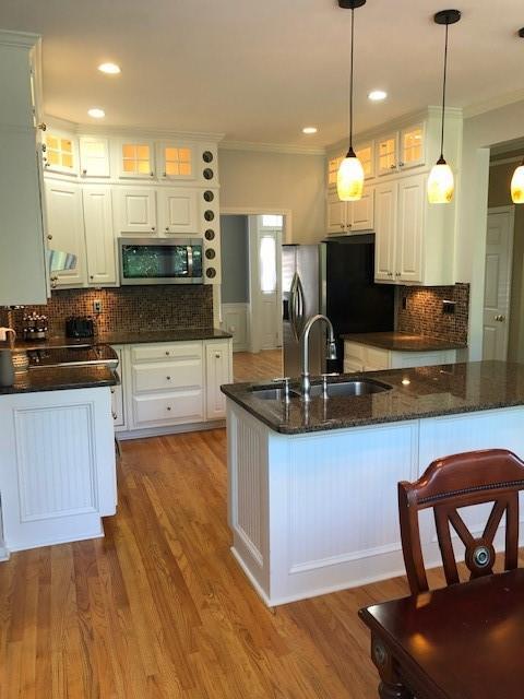kitchen featuring white cabinetry, sink, hanging light fixtures, and appliances with stainless steel finishes